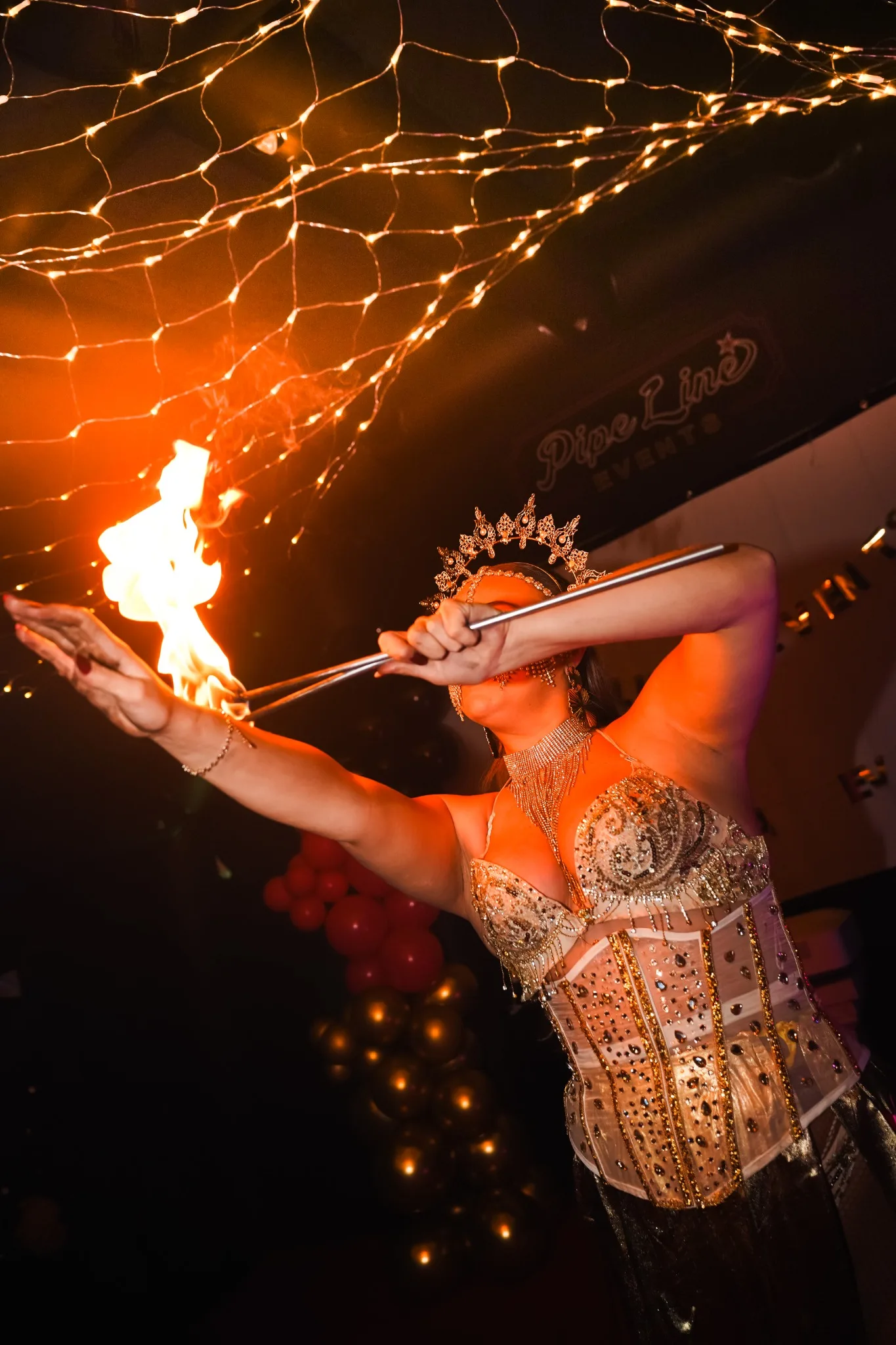 Performer with LED wings dancing under fairy lights in the marquee