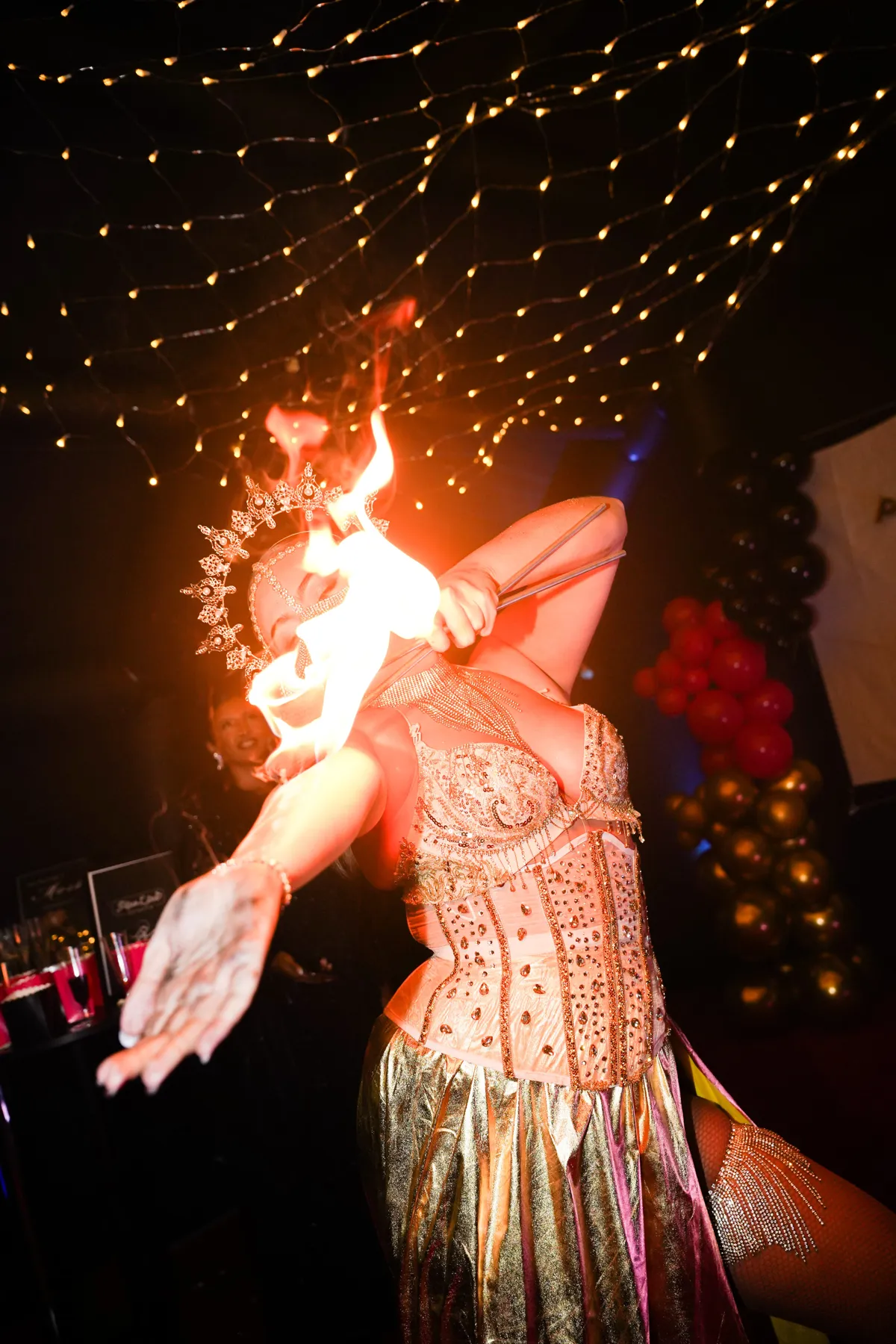 Fire performer under fairy lights at a party in the Suite