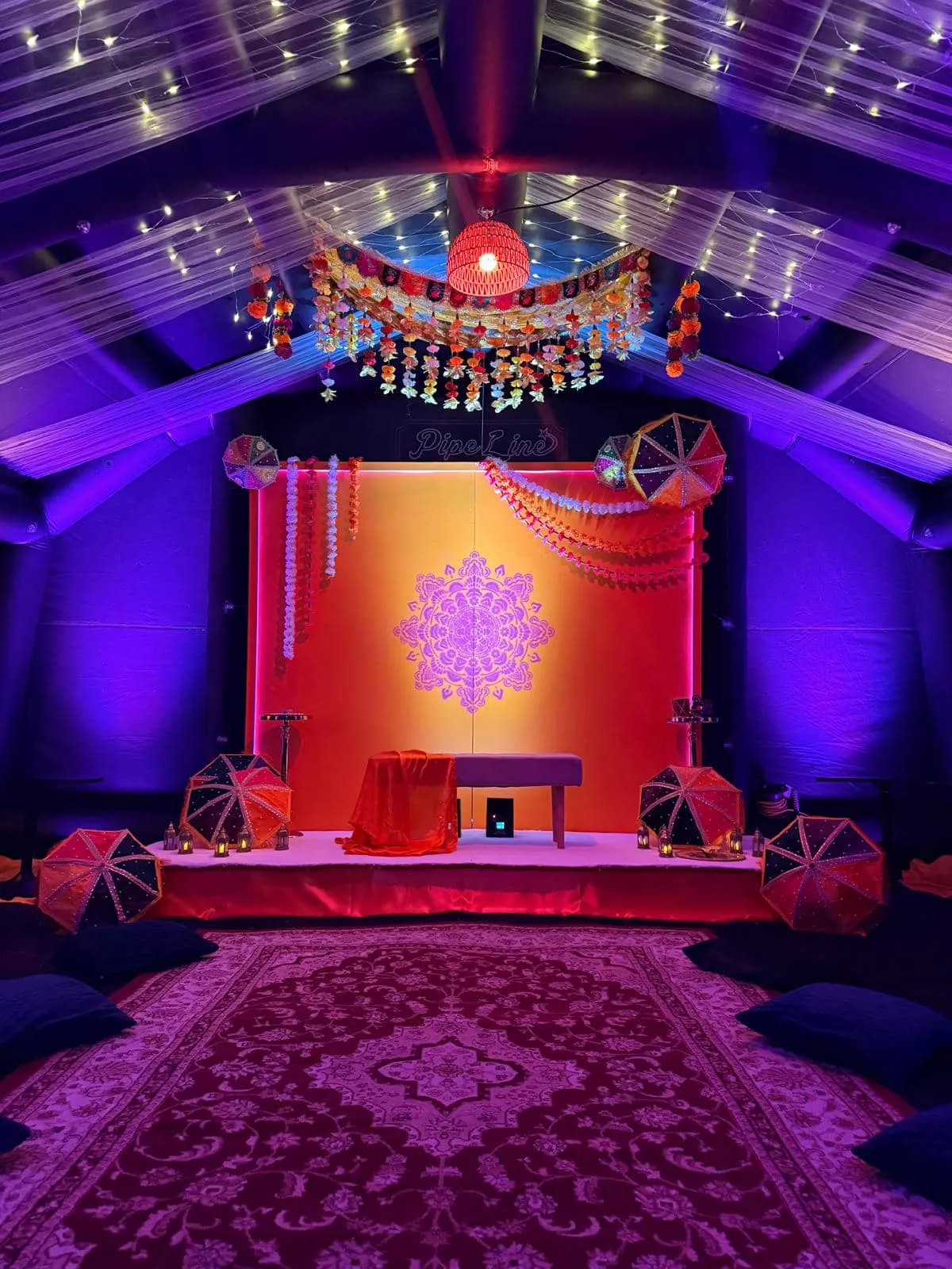The same Suite styled for a mehndi with stage, backdrop, garlands, rug and floor cushions