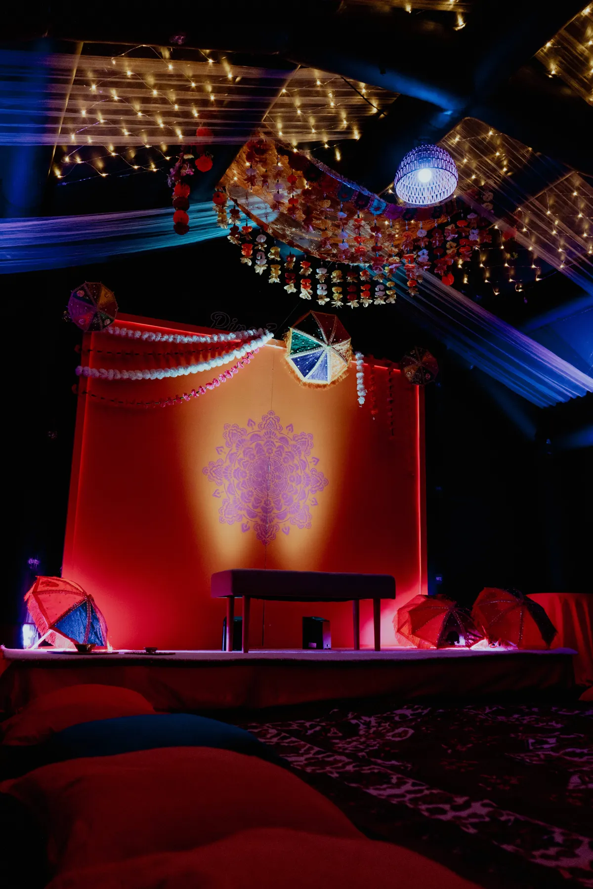 Mehndi stage with mandala backdrop, garlands, umbrellas and fairy light draping