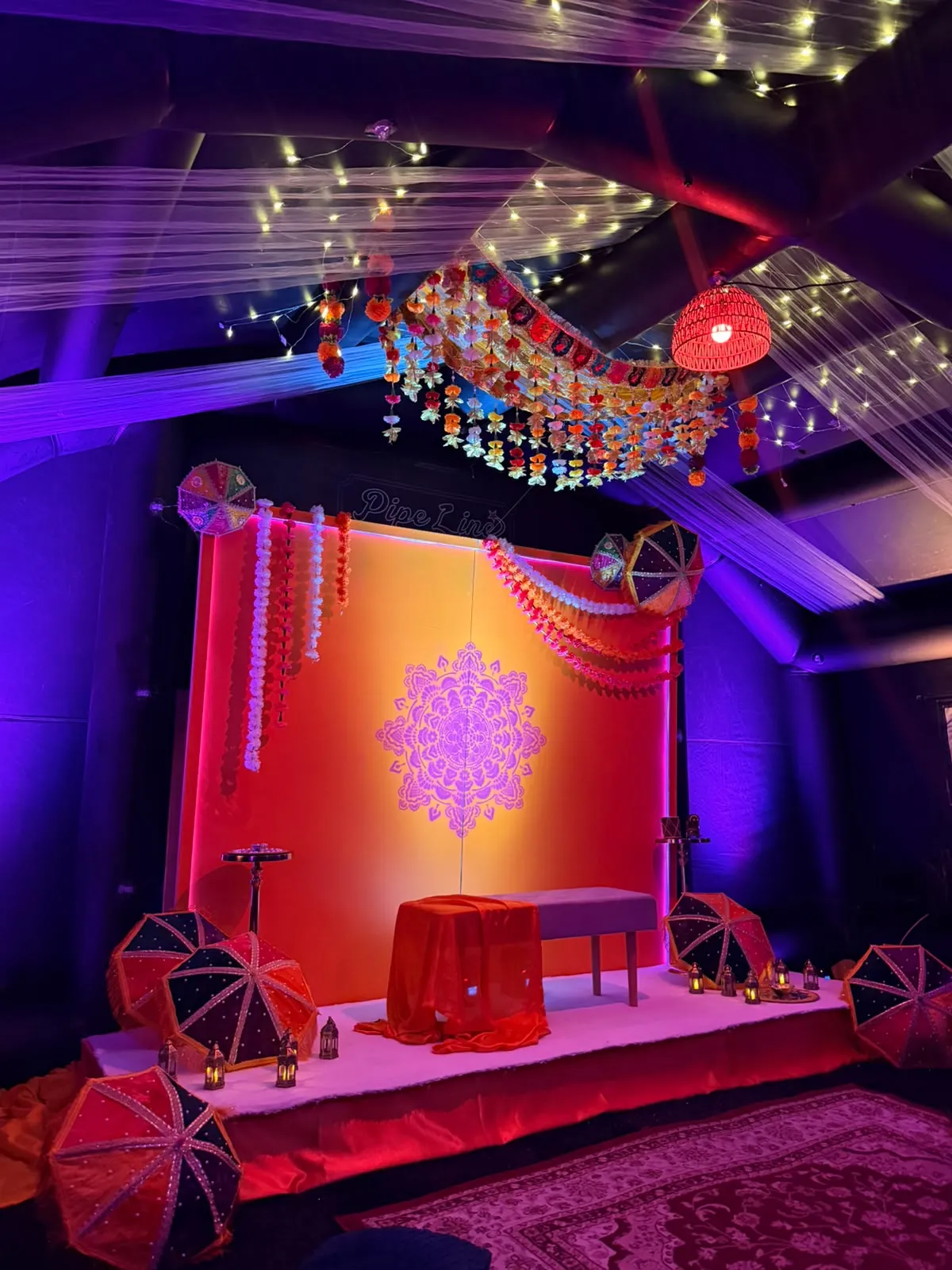 Mehndi stage with mandala backdrop and umbrellas